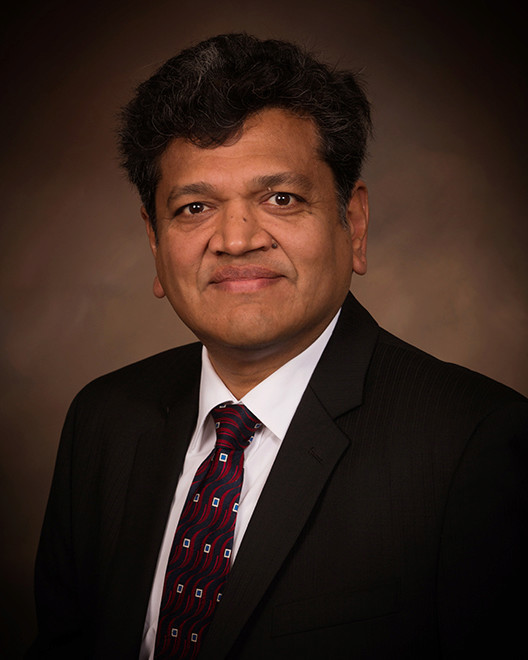 Headshot of Associate Dean Sneha Kasera. He is in a black suit and a red speckled tie.