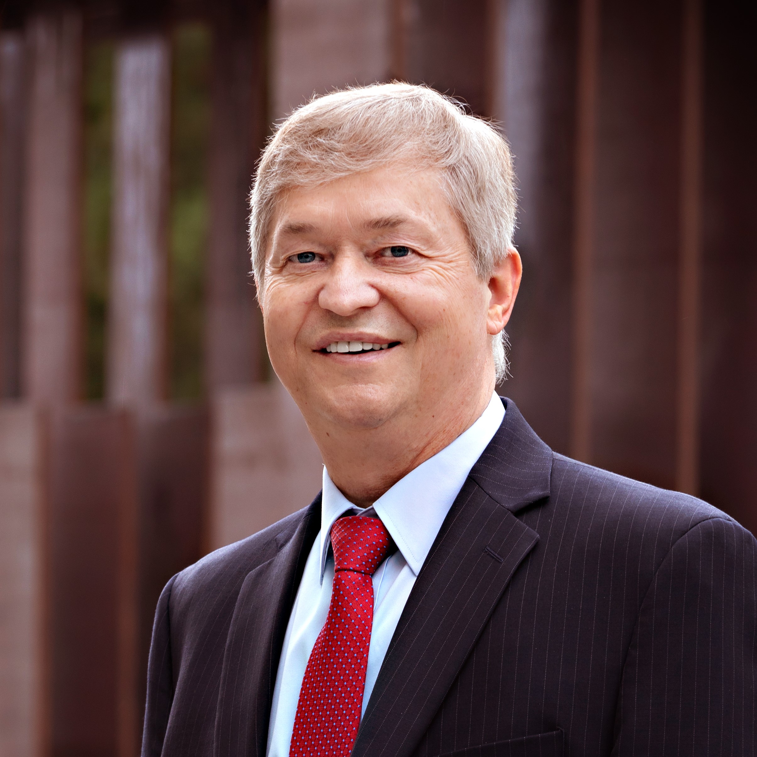 Headshot of Dean Richard Brown in red tie, white shirt, and a black blazer.