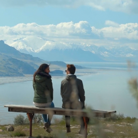 Two people sit facing the Great Salt Lake on a hazy day.