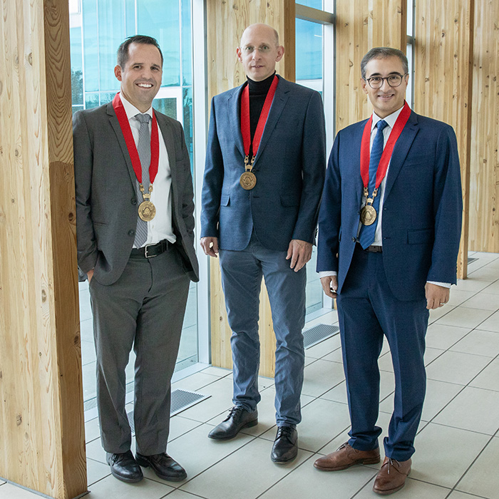 Three new endowed professors pose with medals
