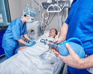 Healthcare workers in PPE prepare to use a ventilator on a patient