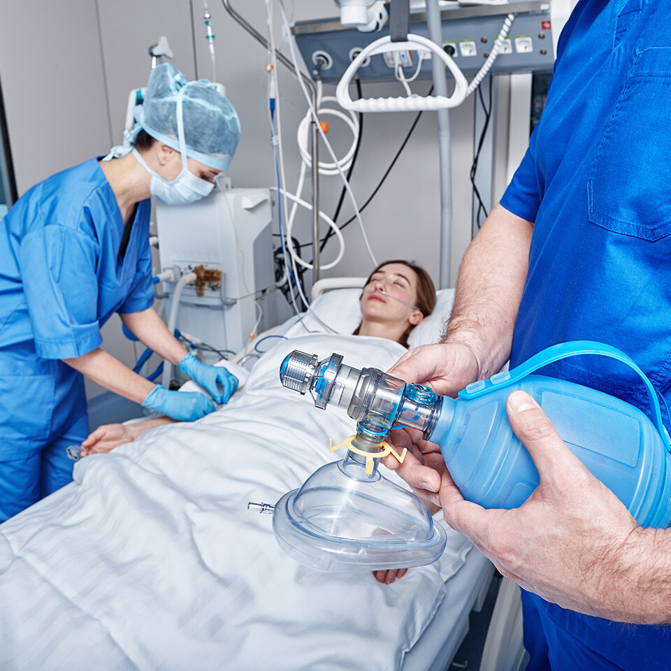 Healthcare workers in PPE prepare to use a ventilator on a patient