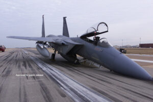 A fighter jet with a badly bent front landing gear sits uselessly on a tarmac.