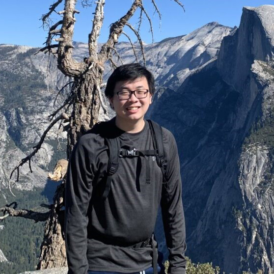 headshot of outstanding dissertation 2025 recipient Johnathan Le. He is pictured at the top of a mountain smiling at the camera
