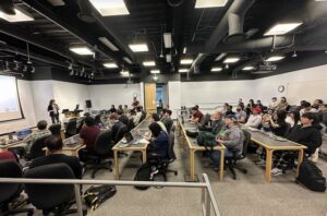 A crowded computer lab with a speaker at the front