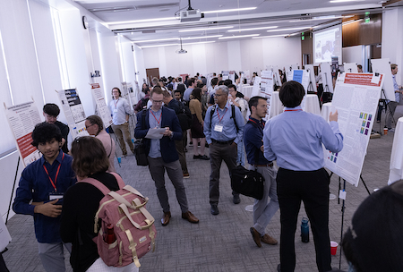 A crowded room filled with students talking in front of easels.