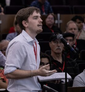 A man with a notebook asks a question from the crowd. 